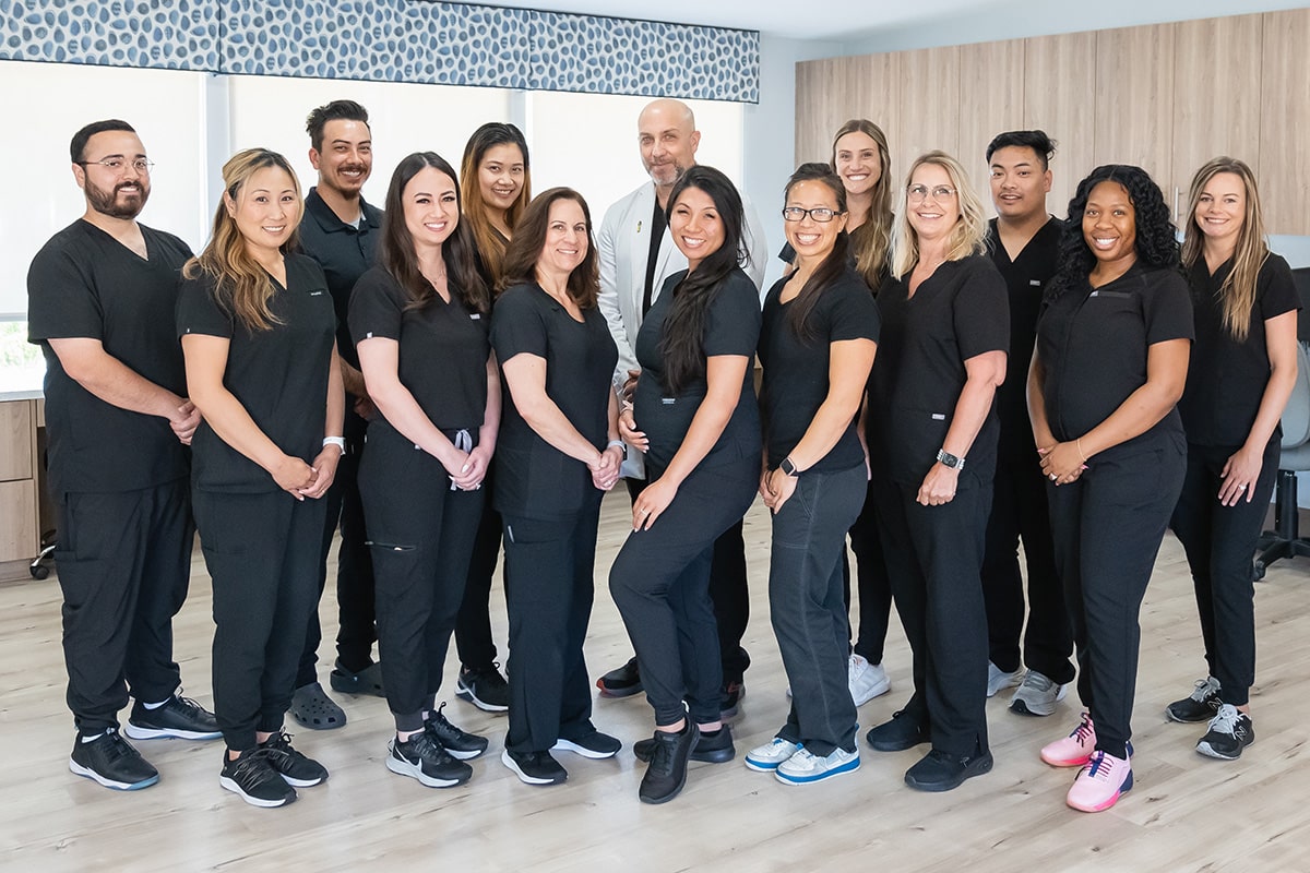 Staff all smiling in black scrubs