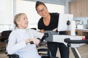 Woman on rower with help from healthcare worker