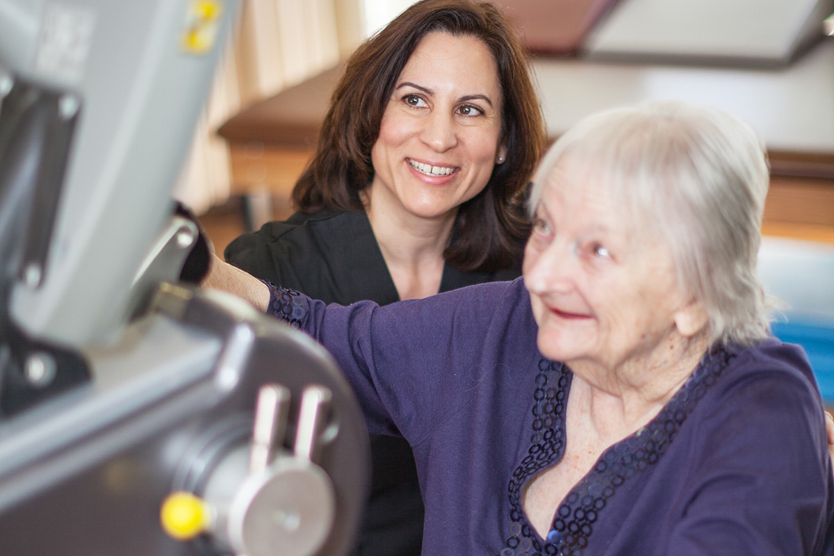 Medical worker helping woman with row machine
