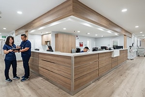 Lobby front desk with two healthcare workers in scrubs.